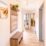 Flur mit Holzboden, Wandgarderobe und Sitzbank. Bilder an den Wänden.