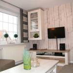 Wohnzimmer mit Fernseher, Glasvitrine und Fenster mit Blick.