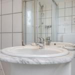 Badezimmer mit Waschbecken, Spiegel und Dusche.