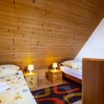 Zwei Betten mit Nachttischen und Lampen unter Holzdecke