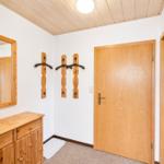 Eingangsbereich mit Holzschrank, Spiegel und Wandhalterungen