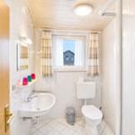 Badezimmer mit Waschbecken, Toilette und Fenster mit Blick.