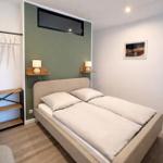 Schlafzimmer mit Doppelbett, grüner Wand und integrierten Nachttischen.