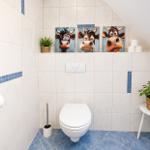 Badezimmer mit Toilette, drei Kuh-Bildern und Pflanzen.