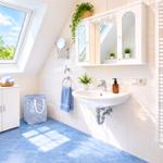 Badezimmer mit Dachschrägenfenster, Waschbecken, Spiegelschrank und Heizkörper mit Handtüchern.