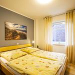 Schlafzimmer mit Doppelbett, Fenster und Gardinen. Wandbild und Nachttische.