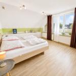 Schlafzimmer mit Doppelbett, Holzboden und großem Fenster mit Blick nach draußen.