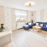 Wohnzimmer mit blauem Sofa, Holztisch und Fenster mit Blick auf Dach.