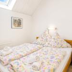 Schlafzimmer mit Doppelbett, Blumenbezug und Dachfenster.