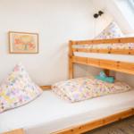 Ein Schlafzimmer mit einem Doppelstockbett aus Holz und einem Fenster.