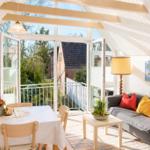 Wohn- und Essbereich mit Balkon, Sofa und Esstisch unter Holzbalken.
