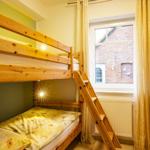 Zimmer mit Holzbett, Fenster und Kleiderschrank