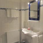 Badezimmer mit Waschbecken, Spiegel, Handtüchern und Heizkörper.
