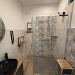 Bad mit Dusche, Waschbecken und Holzregalen