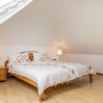 Schlafzimmer mit Dachschrägen, Bett, Nachttische und Stuhl.