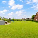 Großer grüner Garten mit Spielplatz, Grill und Fußballtor neben einem Haus.