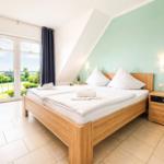 Schlafzimmer mit Doppelbett, Balkon und grüner Wand.