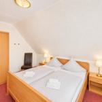 Schlafzimmer mit Doppelbett, Nachttischen und Kleiderschrank unter schrägem Dach.