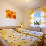 Schlafzimmer mit Doppelbett, Fenster und Wandbild.