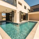 Moderne Villa mit Pool und Terrasse. Glasfronten öffnen sich zum Außenbereich.
