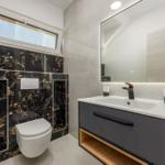 Badezimmer mit schwarzer Marmorwand, Waschtisch und Toilette.
