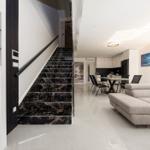 Modernes Wohnzimmer mit schwarzem Marmor-Treppenhaus und grauem Sofa.