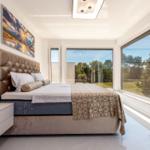 Schlafzimmer mit großem Bett, Fenstern und Wandbild.