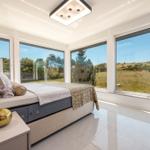 Schlafzimmer mit großem Bett und Fenstern zur Landschaft.