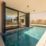Pool mit Blick auf Wohnbereich durch große Glastüren.
