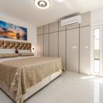 Schlafzimmer mit großem Bett, Wandbild und bodentiefen Schiebetüren zur Terrasse.
