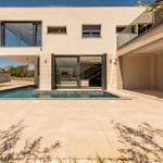 Moderne Villa mit Pool und Terrasse. Glasfront öffnet sich zum Innenraum.