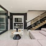 Moderne Wohnfläche mit Sofa, Tisch und Glasgeländer-Treppe.