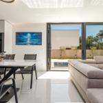Wohn- und Essbereich mit Blick auf Pool und Garten. Moderne Einrichtung und Glaswände.