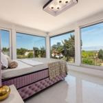 Schlafzimmer mit großem Fenster und Blick auf Landschaft.