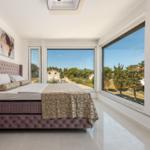 Schlafzimmer mit großem Bett und Blick auf Außenbereich durch Fenster
