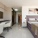 Schlafzimmer mit Bett, Schreibtisch und Spiegelschrank. Fliesenboden und Wandbild.
