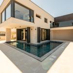 Moderne Villa mit Pool und Terrasse. Glasfassade und Steinmauer.