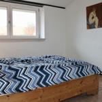 Schlafzimmer mit Bett, Fenster und Wandbild.