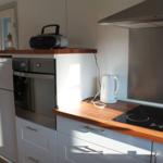Küche mit Herd, Backofen, Kühlschrank und Wasserkocher.