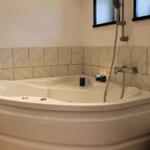 Eckbadewanne mit Duschkopf und Kerzen