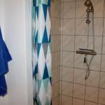 Dusche mit Duschvorhang und blauem Handtuch an der Wand.
