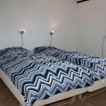 Schlafzimmer mit Doppelbett, blau-weißem Muster, Wandlampen und Fenster mit Radio.