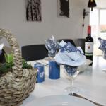 Gedeckter Tisch mit Blumenvase, Kerzen und Weinflasche.