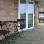 Terrasse mit Holzdecke, Tisch und Stühlen neben einer Glastür.