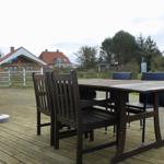 Holzterrasse mit Tisch und Stühlen. Blick auf Garten und Nachbarhäuser.