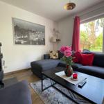 Wohnzimmer mit Sofa, Kamin und Blick auf grünen Garten.