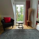 Schlafzimmer mit Sitzgelegenheit und Balkonblick. Holzboden und Teppichboden.