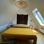 Schlafzimmer mit Dachschräge, gelbem Bett und Dachfenster.