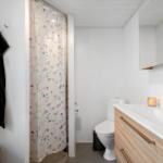 Badezimmer mit Dusche, Toilette und Waschbecken mit Spiegel.