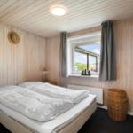 Schlafzimmer mit Bett, Fenster, Vorhängen und Korb.